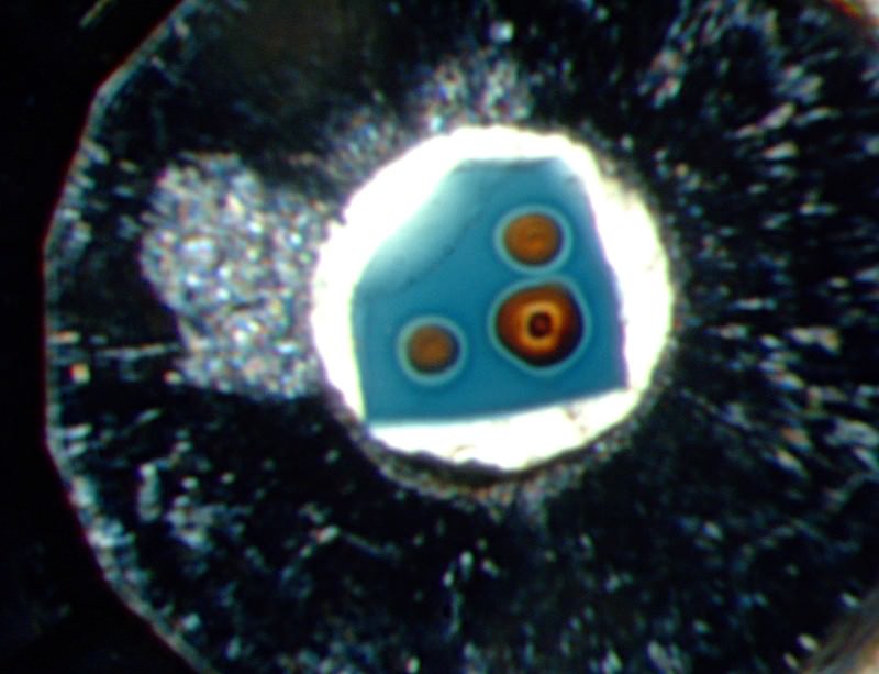 Laboratuvarda deney sırasında ezilen mavi ringwoodite kristali. Turuncu daireler kristalden dışarı sızan suyu gösteriyor.